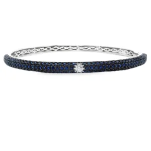 Embrace the epitome of sophistication with this exquisite bangle, meticulously crafted in lustrous 18kt white gold. The design showcases a continuous array of round brilliant-cut sapphires weighing 2.30ct exhibiting a mesmerizing royal blue hue. A central round brilliant-cut diamond weighing 0.12ct and provides a dazzling focal point, creating a harmonious balance between color and brilliance. Diamomnd weight-0.12ct Sapphire weight-2.30ct